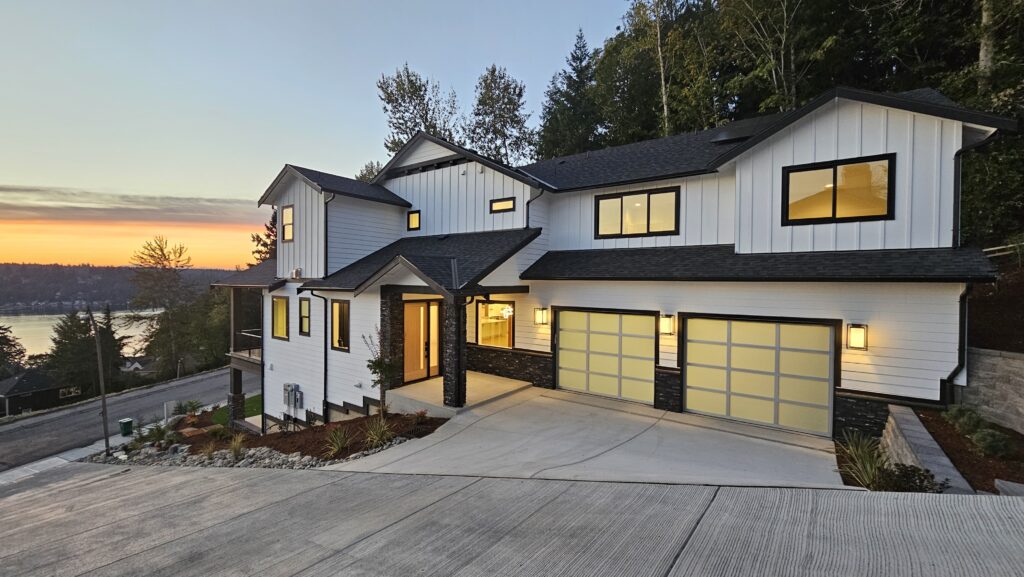Photo of large modern white with black trim home on a hill during sunset with view of Lake Sammamish 