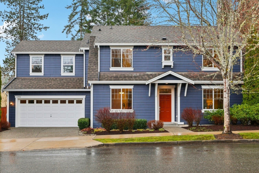 Photo of a light navy blue house with a red door and white trim. 